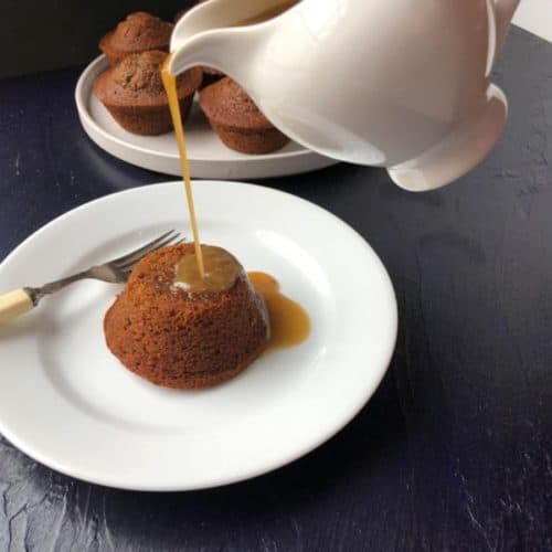 A white jug pouring salted caramel onto a sticky date pudding.