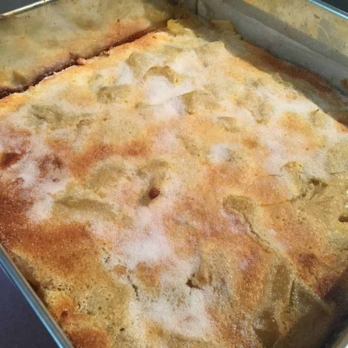 Apple slice in a tin golden brown with sugar sprinkled on the top