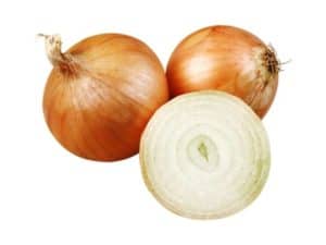 Close up of brown onions. One is sliced in half showing the inside.
