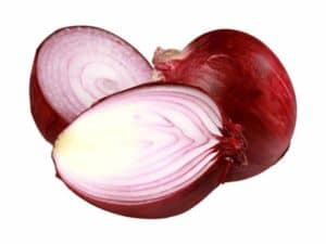 Close up of red onions. One is sliced in half showing the inside.
