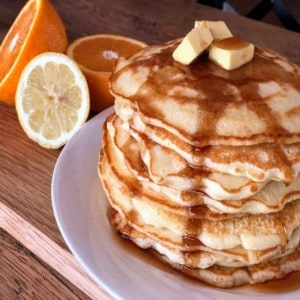 Stack of golden Thermomix pancakes with maple syrup drizzle.