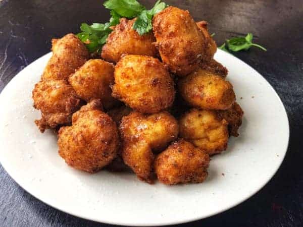 A plate showing fried cheese potato bacon poppers.