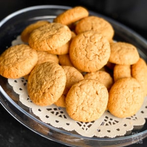 A glass cake stand with a stack of peanut butter cookies on top.