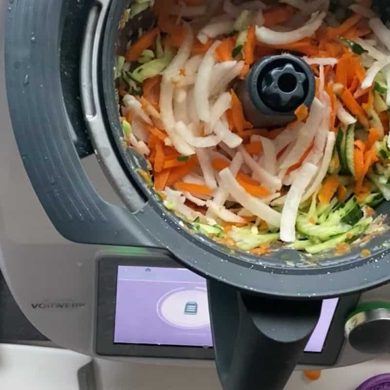 Sliced vegetables in a Thermomix bowl.