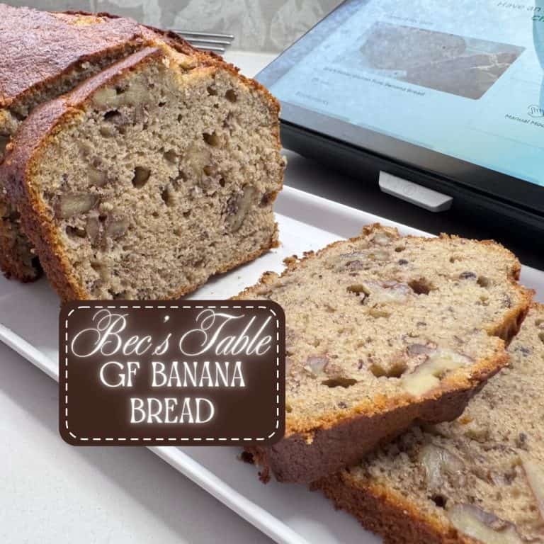 a sweet loaf of banana bread (sliced) on a white rectangular plate, with walnuts visible inside.